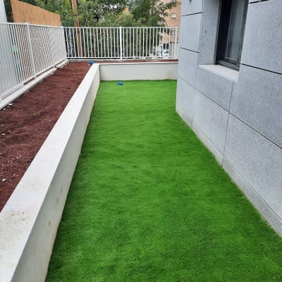 דשא סינתטי וערוגת אדמה לצד גדר לבנה