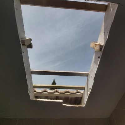 פתח בגג עם קורות עץ ושמיים ברקע