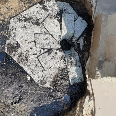 חומר איטום שחור על משטח בטון עם סדקים