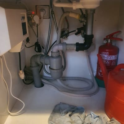 צנרת מתחת לכיור עם ברזים וצינורות