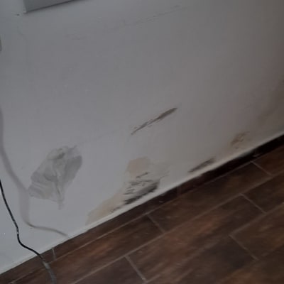 קיר עם כתמי צבע, מברשת ודלי צבע על הרצפה