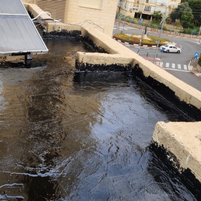 גג אטום בזפת שחורה עם לוחות סולאריים