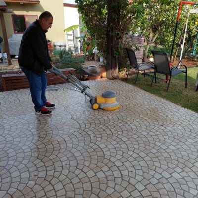 אדם מנקה רצפה עם מכונת פוליש בחצר