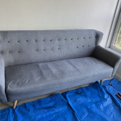 ספה אפורה על יריעת פלסטיק כחולה עם מברשת ניקוי