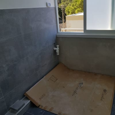 קרטון על רצפה, צינור מים, קיר מחופה אריחים