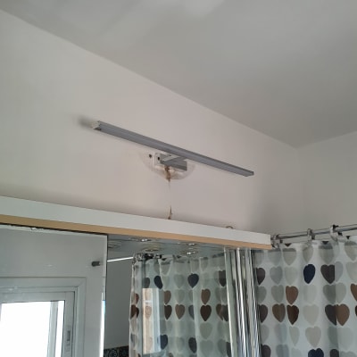 מנורת קיר מותקנת מעל מראה בחדר אמבטיה