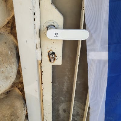 ידית דלת לבנה עם מנעול על דלת מתכת חלודה