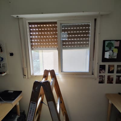 תריסים חומים חצי פתוחים על חלון לבן