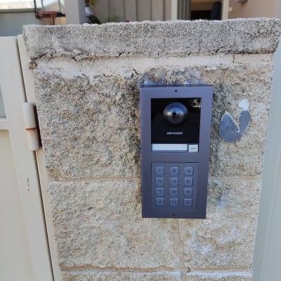 אינטרקום עם מצלמה ומקשים על קיר אבן