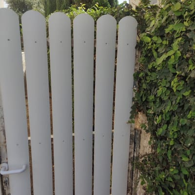 שער עץ לבן עם צמחייה ירוקה מסביב