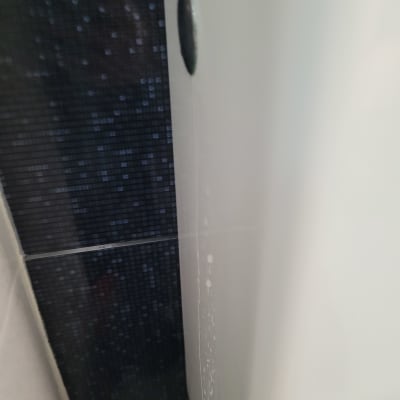 קיר אריחים כהים עם סימני נזילה ליד חיבור אמבטיה