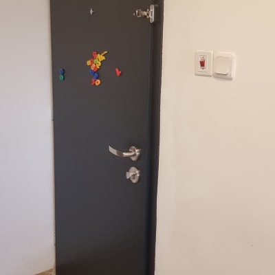 דלת שחורה עם ידית מתכת ודלי צבע אדום