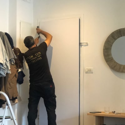 אדם מתקין ציפוי על דלת בעזרת כלי עבודה
