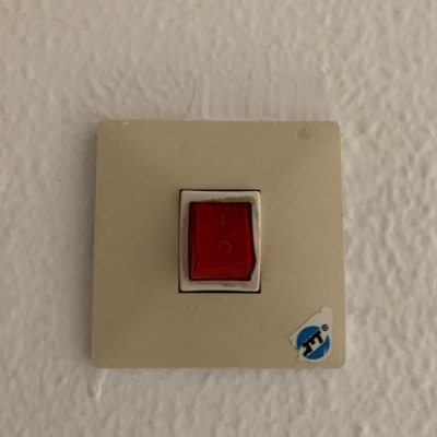 מתג חשמלי עם כפתור אדום על קיר לבן