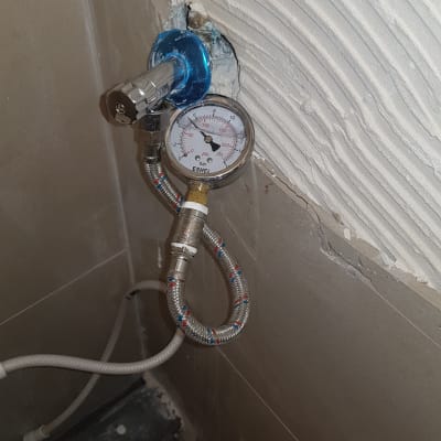 מד לחץ מים מחובר לצינור מתכת בקיר