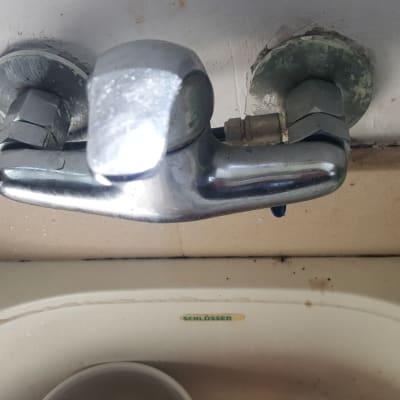 ברז מתכת מותקן על קיר מעל כיור