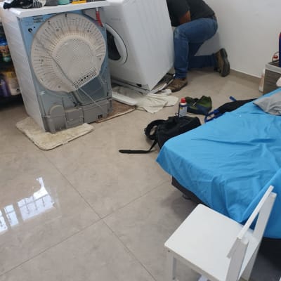 אדם מתקן מכונת כביסה בחדר עם כלים