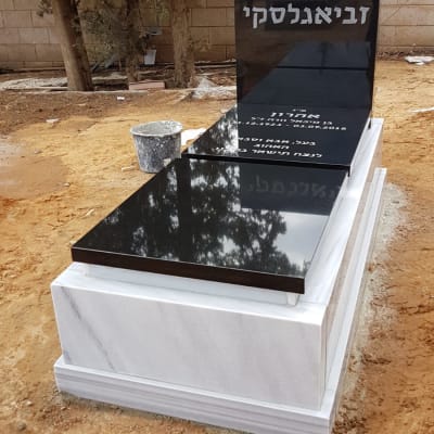 מצבה שחורה עם כיתוב לבן בבית קברות