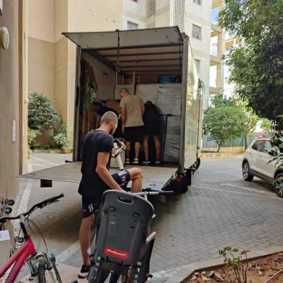 אנשים מעמיסים משאית הובלה עם רהיטים וארגזים