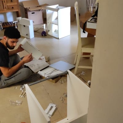 אדם מרכיב רהיט עם חלקים וכלים על הרצפה