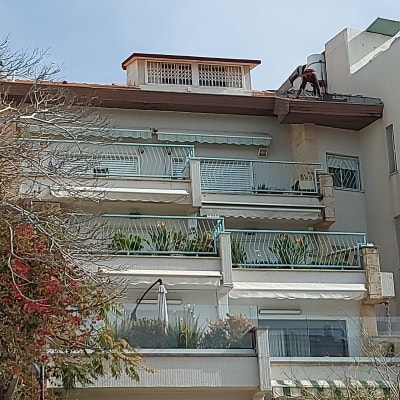 אדם עובד על גג עם רעפים אדומים