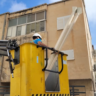 אדם במנוף עם קסדה ליד גג בניין