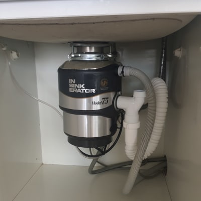 מכשיר טוחן אשפה מותקן מתחת לכיור עם צינורות מחוברים