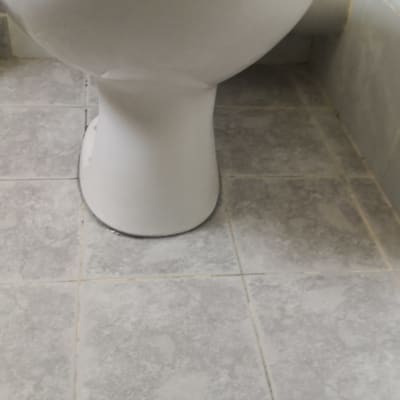 אסלה לבנה על רצפת אריחים אפורה