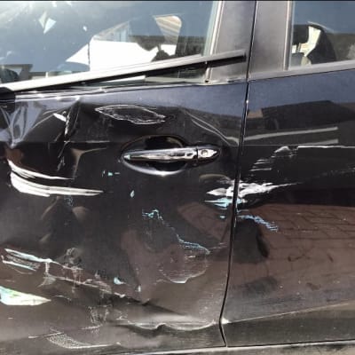 נזק לדלת רכב שחור עם שריטות ושקעים