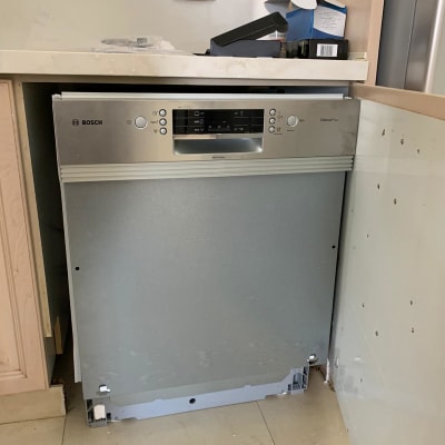 מדיח כלים מותקן חלקית במטבח עם כלים על השיש