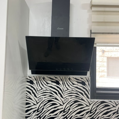 קולט אדים שחור מותקן מעל כיריים במטבח