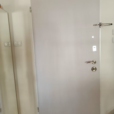 דלת לבנה עם ידית מתכת ובריח עליון