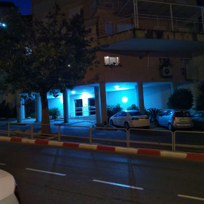 בניין עם תאורה כחולה בלילה, מכוניות חונות