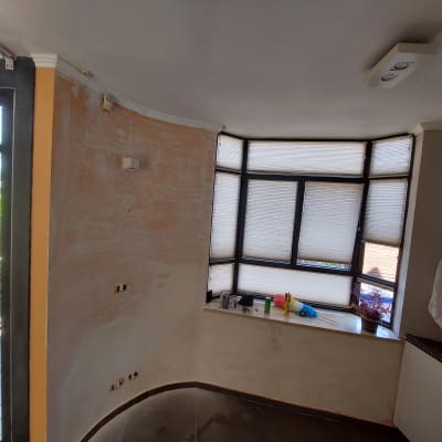 קיר צבוע חלקית עם חלון גדול וכלי עבודה על אדן החלון