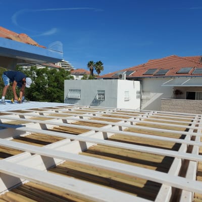 אדם עובד על גג עץ עם כלי עבודה