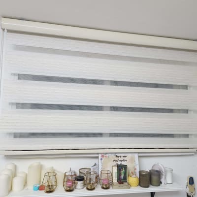 וילון גלילה לבן עם פסים שקופים על חלון