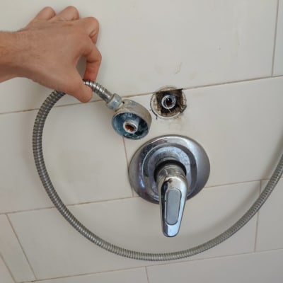 יד מחזיקה צינור מקלחת מנותק עם חלודה