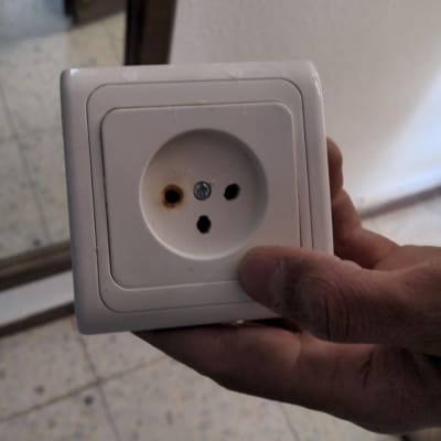 שקע חשמלי עם סימני שריפה מוחזק ביד