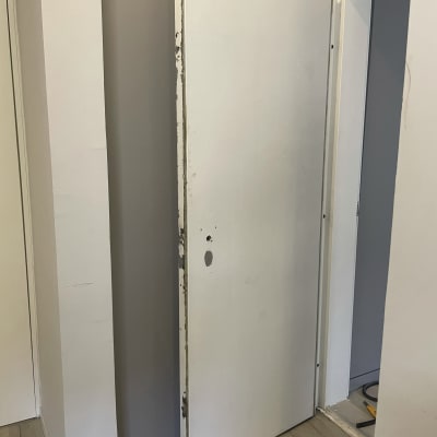 דלת לבנה עם קילופים ותיקונים בצדדים