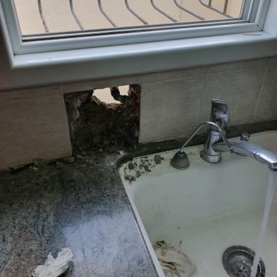 כיור מטבח עם חור בקיר וצינור חשוף