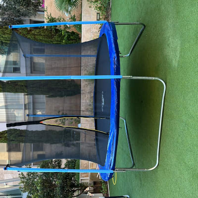 טרמפולינה עם רשת בטיחות על דשא ירוק