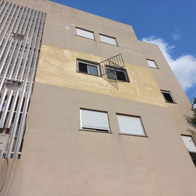 בניין עם חלונות ותריסים, סורג מתכת על חלון אחד