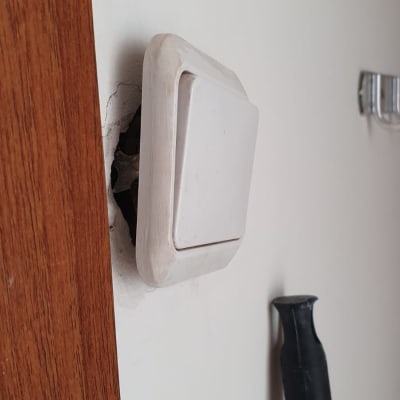 מתג חשמל רופף בקיר עם סדקים