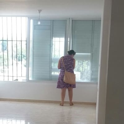 אישה עומדת ליד חלון עם תריסים סגורים