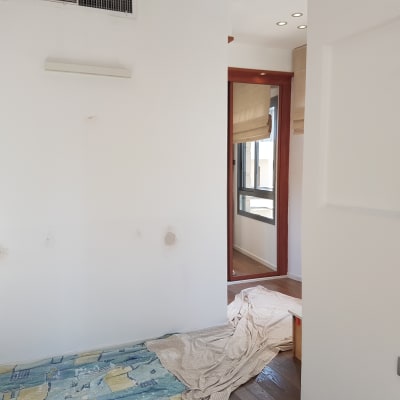 קיר לבן עם תיקוני צבע ויריעת בד על הרצפה