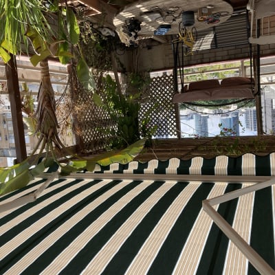 סוכך פסים ירוק ולבן במרפסת עם צמחים תלויים