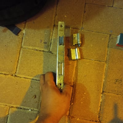 יד מחזיקה מנעול עם צילינדרים על רצפה מרוצפת