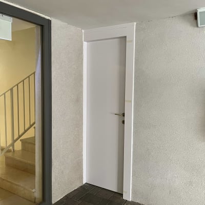 דלת לבנה עם ידית זהב בקיר בטון