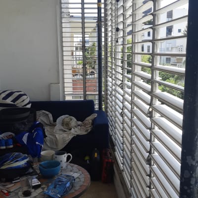 תריסים לבנים אנכיים במרפסת עם נוף עירוני