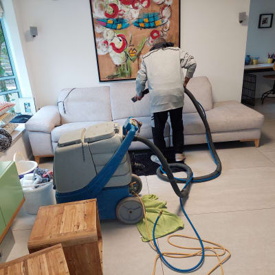 אדם מנקה ספה עם מכונת ניקוי מקצועית